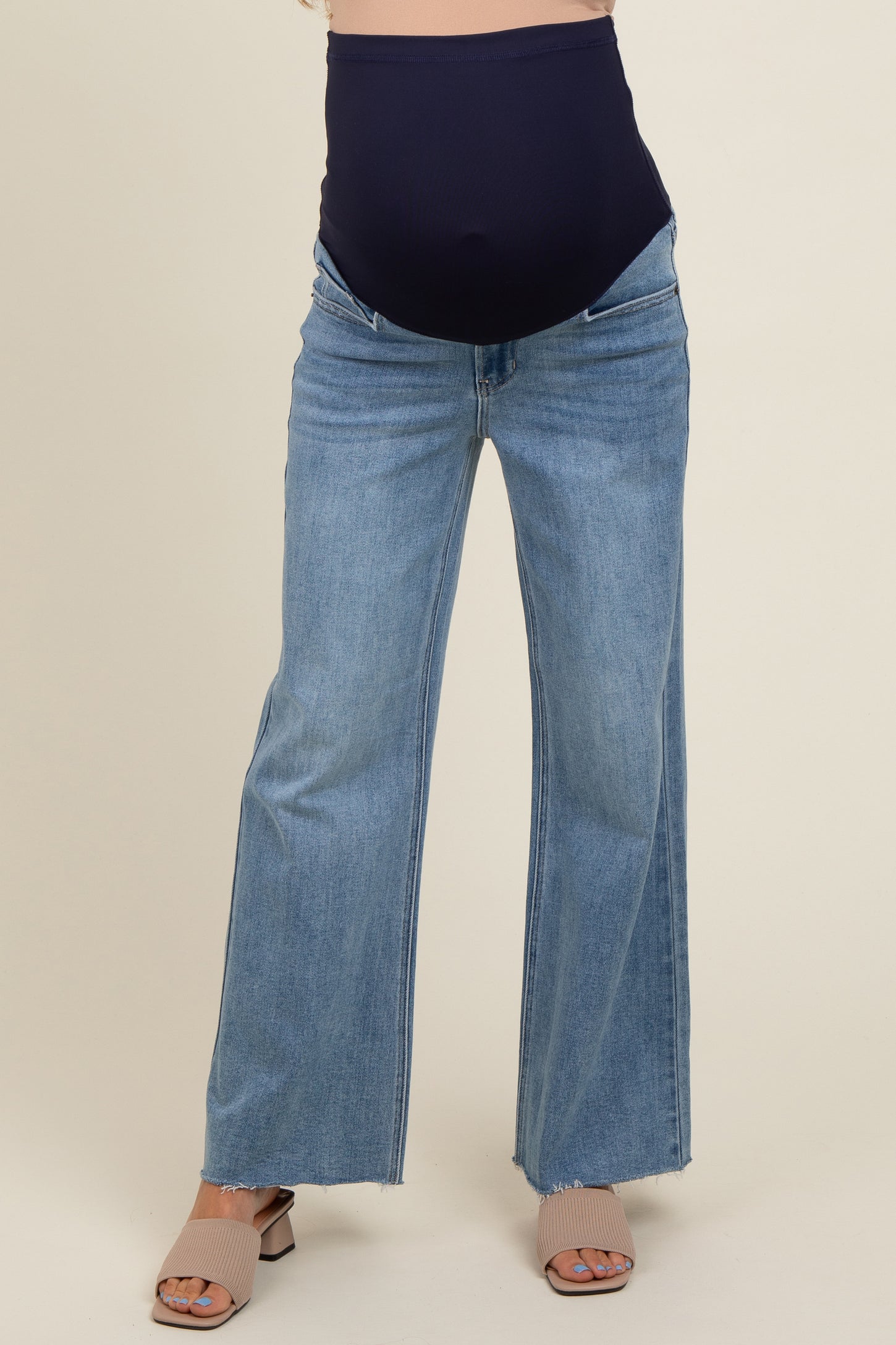 woman wearing a navy maternity belly band with light blue wide-leg maternity jeans, showing a baby bump