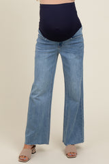 woman wearing a navy maternity belly band with light blue wide-leg maternity jeans, showing a baby bump