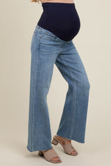 woman wearing light blue maternity jeans with a flared leg and a navy top, showcasing a visible baby bump