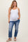 woman wearing a white maternity tank top and distressed blue maternity plus jeans, showing her baby bump