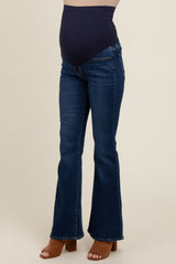 woman wearing dark blue flared maternity jeans with a supportive belly band and a visible baby bump