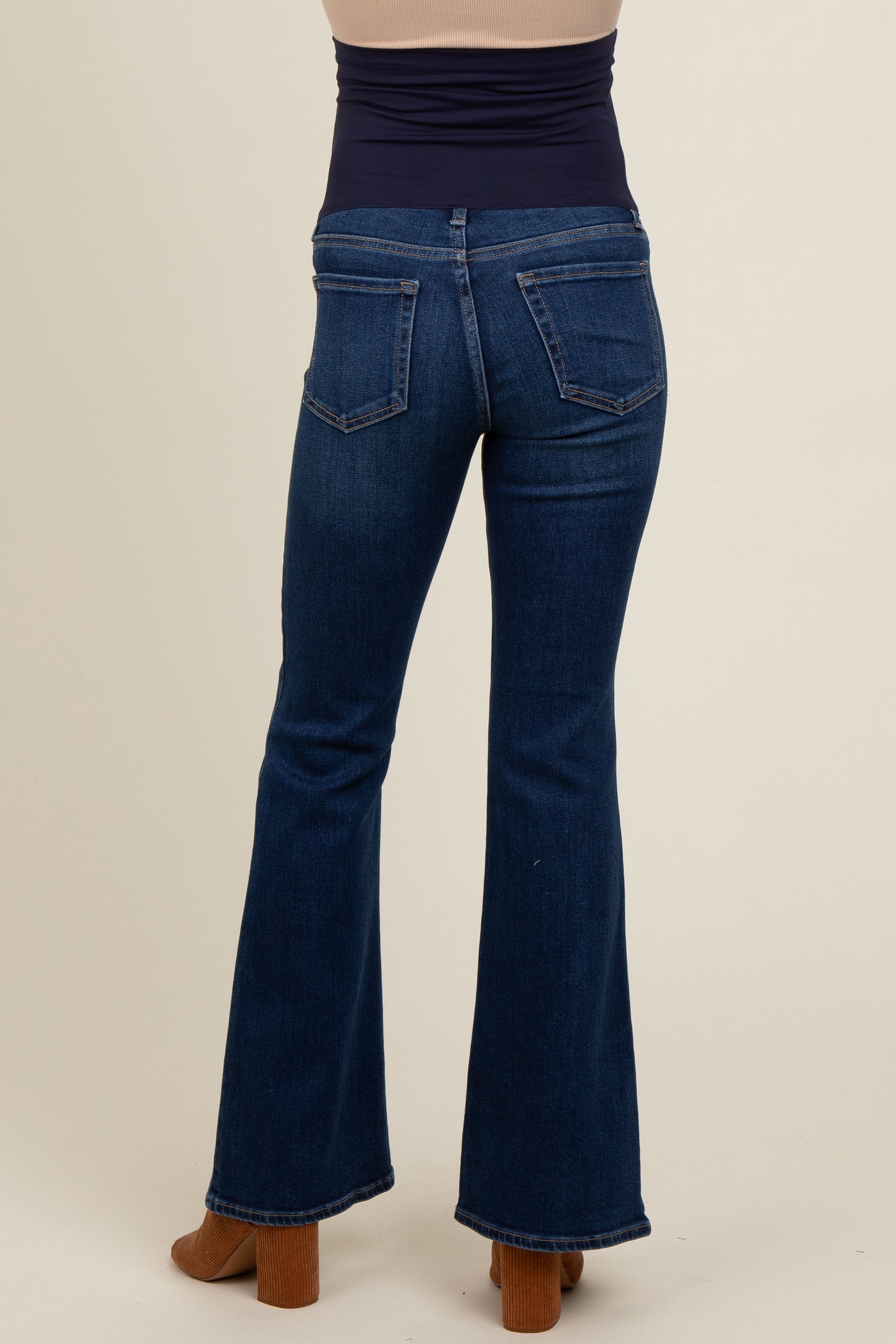 woman wearing a pair of dark blue maternity flared jeans, viewed from the back, showcasing a high waist design