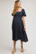 woman wearing a navy blue floral print maternity dress with a square neckline and short puff sleeves, showing her baby bump