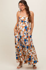 woman wearing a patterned maxi maternity dress with a cinched waist and adjustable straps, showcasing her baby bump