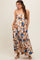 woman wearing a patterned maxi maternity dress with a cinched waist and adjustable straps, showcasing her baby bump