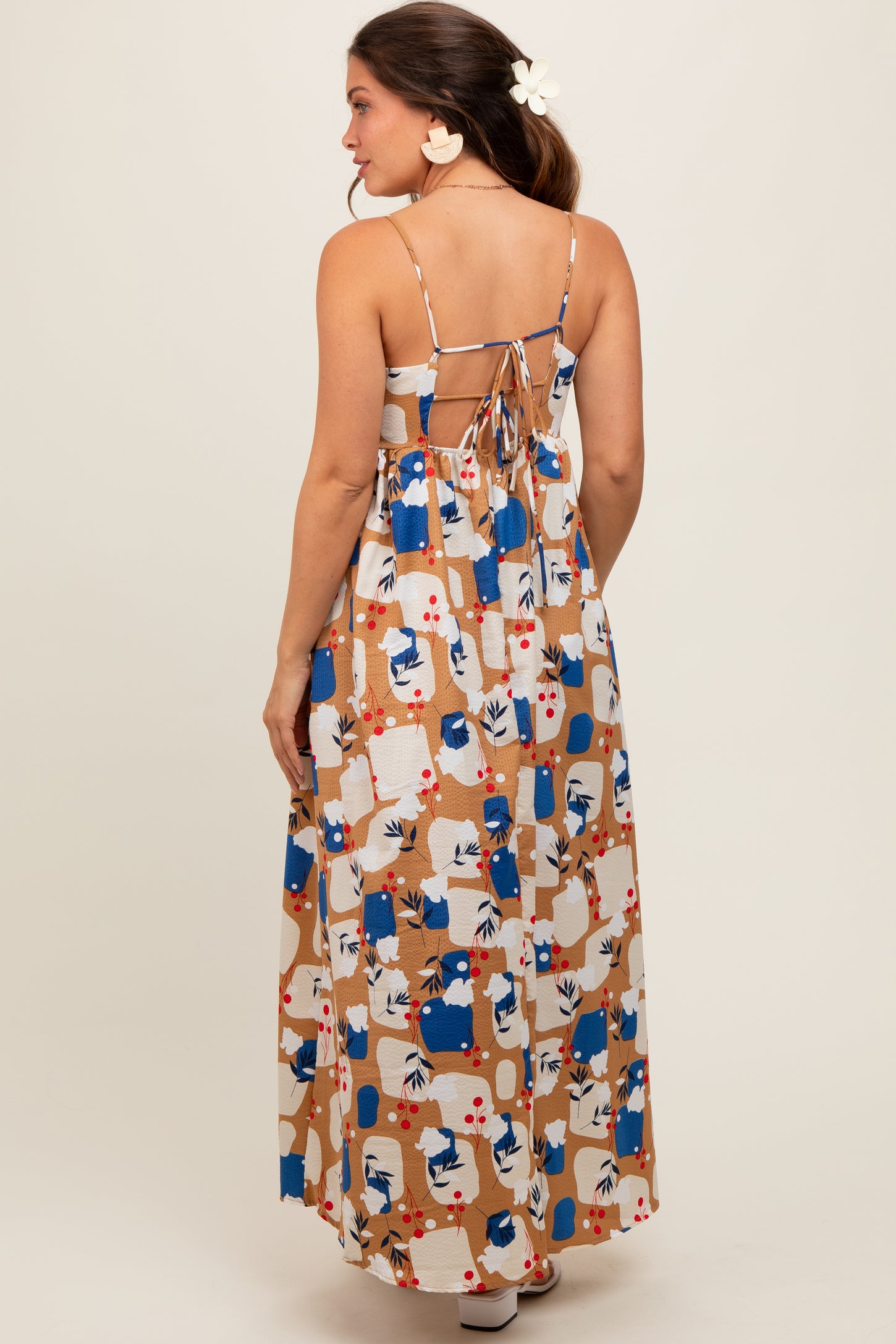 woman wearing a colorful patterned maternity maxi dress with adjustable spaghetti straps and an open back design