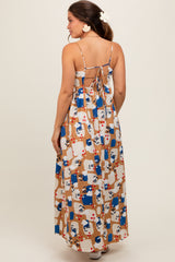 woman wearing a colorful patterned maternity maxi dress with adjustable spaghetti straps and an open back design