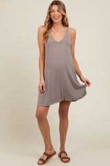woman wearing a taupe maternity tank dress with a v-neckline and flowy hem, standing and smiling