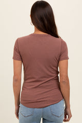woman wearing a mauve short sleeve ribbed maternity top, seen from the back, with light blue jeans