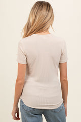 woman wearing a light beige short sleeve maternity top, seen from the back, paired with denim jeans