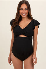 woman wearing a black maternity one-piece swimsuit with ruffle sleeves and a cutout detail, showing her baby bump