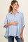 woman wearing a light blue striped maternity shirt and holding her baby bump