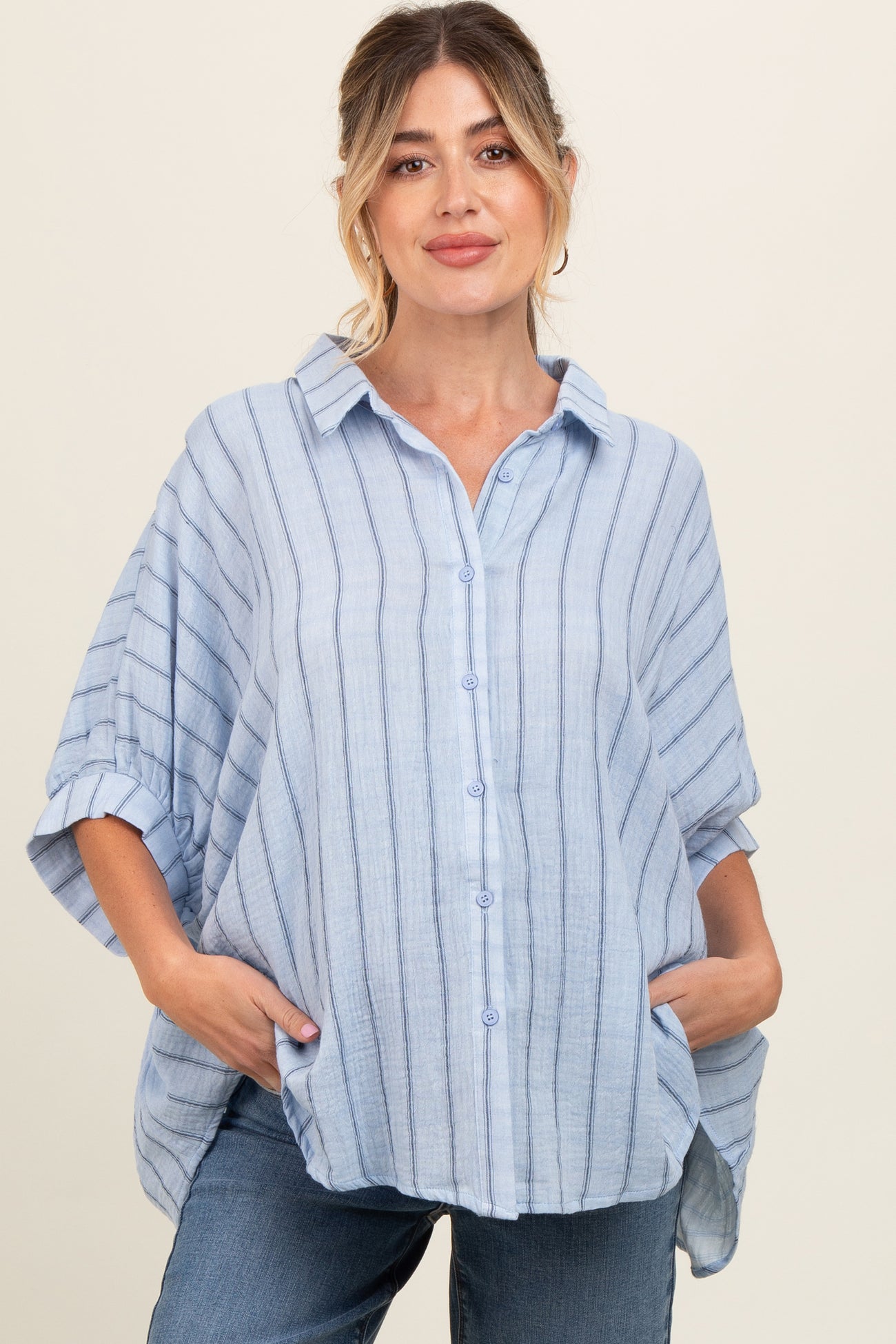 woman wearing a light blue striped maternity top with a button-up front and relaxed fit