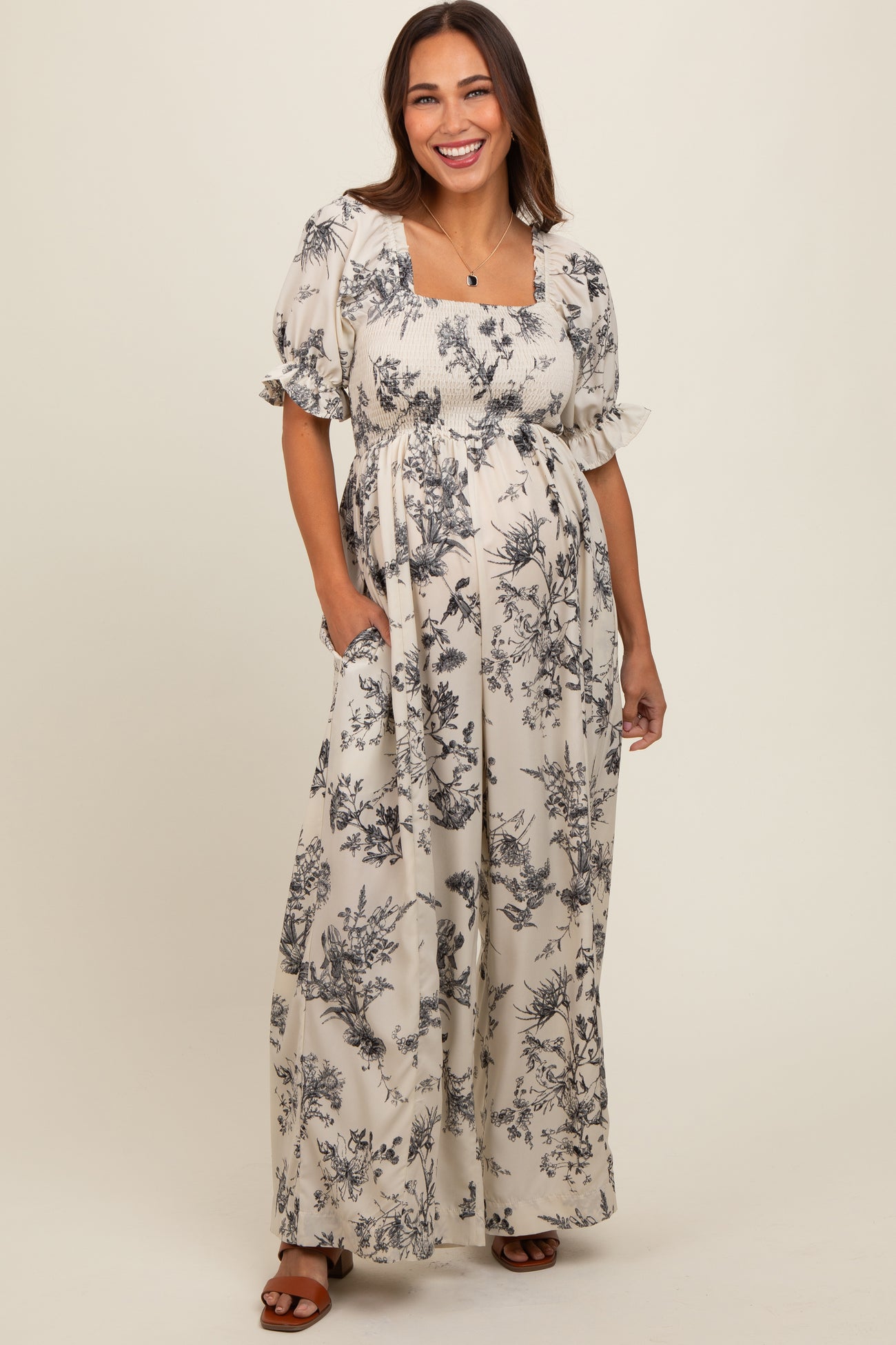 woman wearing a floral print maternity maxi dress with puff sleeves and a square neckline, holding her baby bump