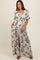 woman wearing a beige floral print maternity jumpsuit with smocked bodice and flowy wide legs, showcasing her baby bump