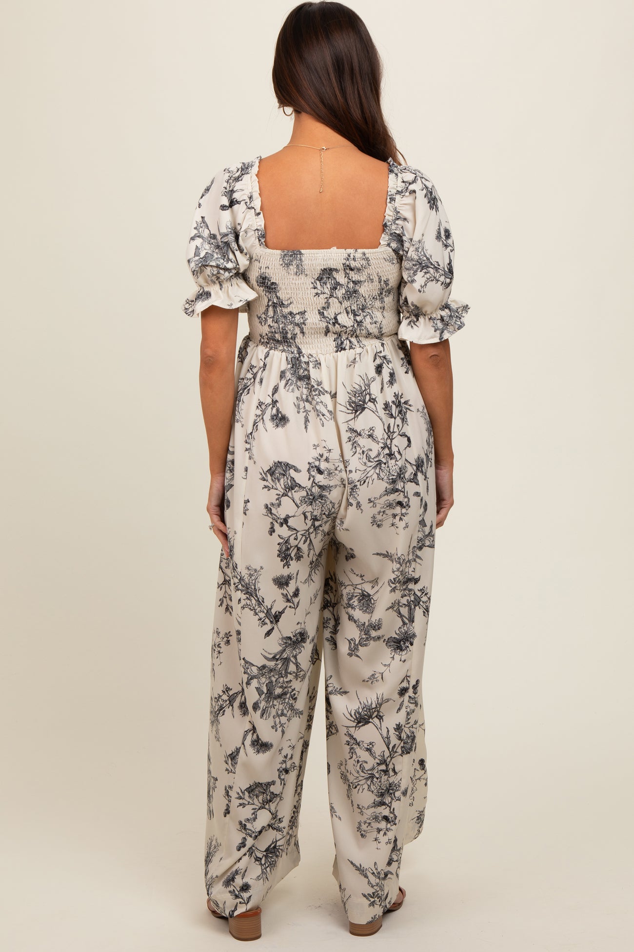woman wearing a maternity floral jumpsuit with short puff sleeves and a smocked back, showing a relaxed fit