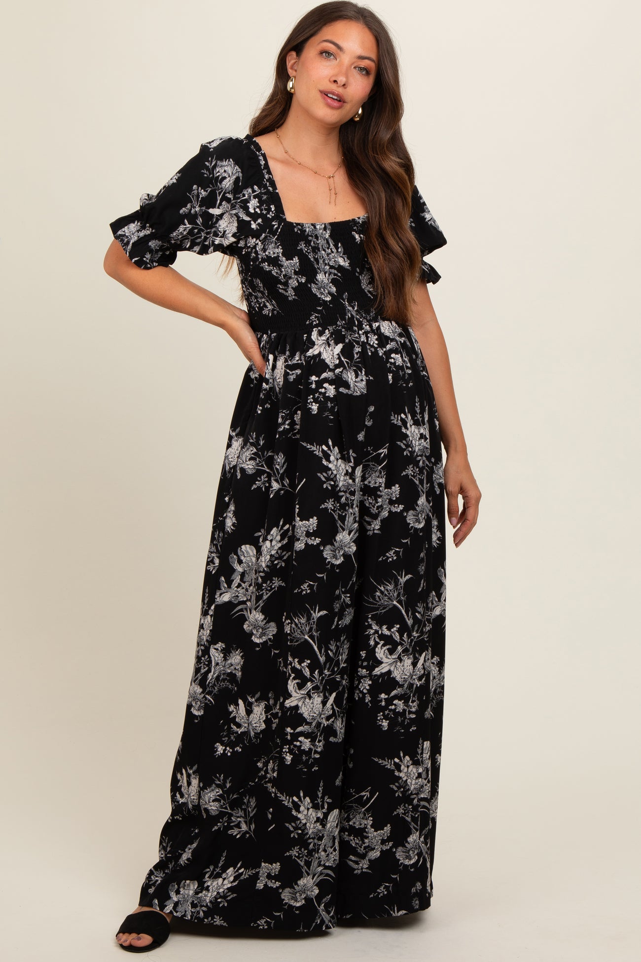 woman wearing a black floral printed maternity dress with puff sleeves and a square neckline, displaying her baby bump