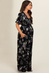 woman wearing a black floral maternity maxi dress with short sleeves and pockets, showcasing her baby bump