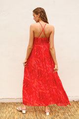 woman wearing a long red floral maxi dress with a strappy back design and a flowing silhouette