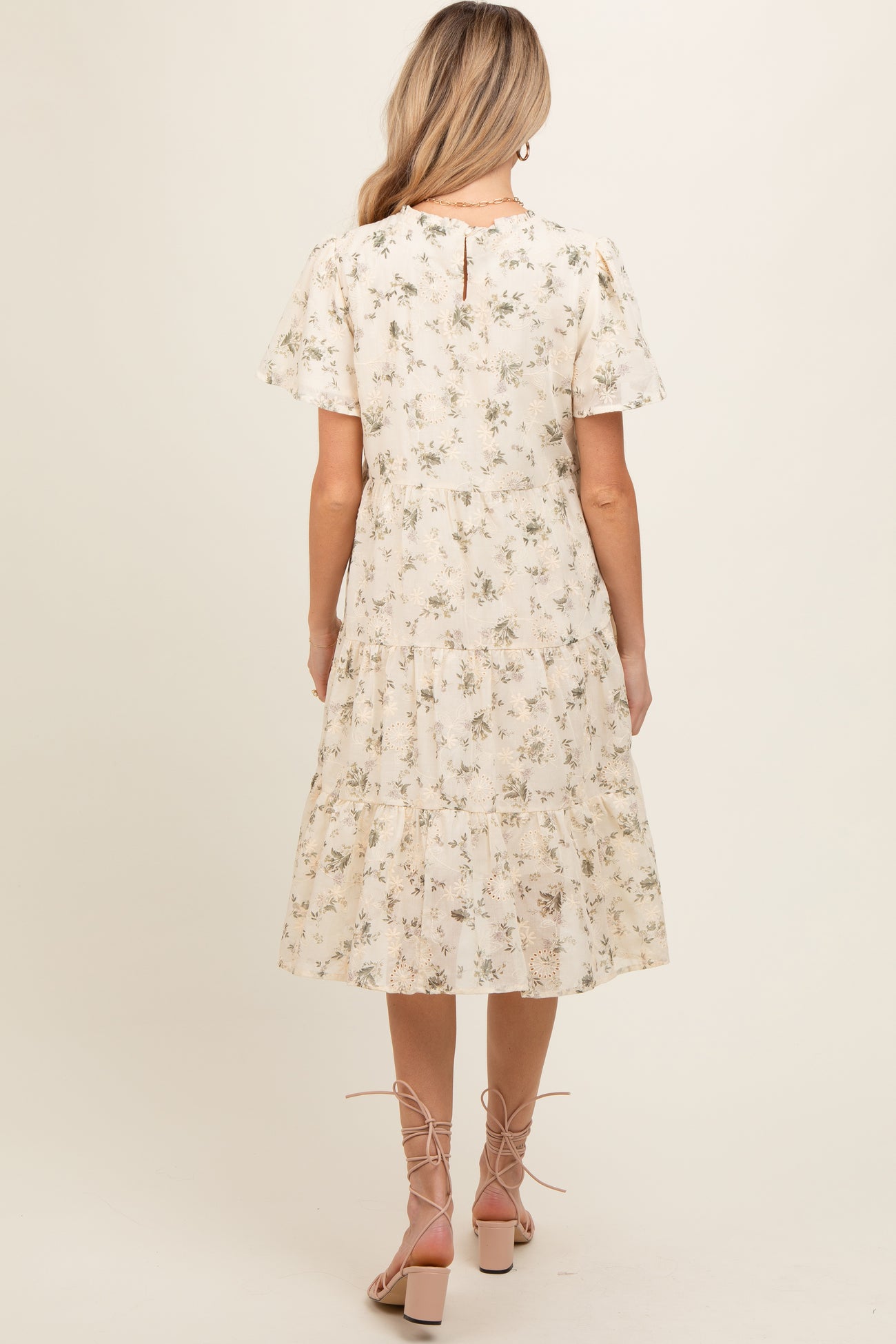 woman wearing a floral maternity dress with short sleeves and a tiered skirt, showing a baby bump from the back