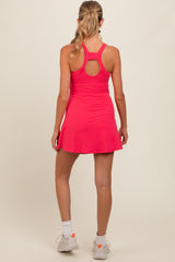 woman wearing a bright pink maternity dress with a racerback style and flared skirt, showcasing her baby bump