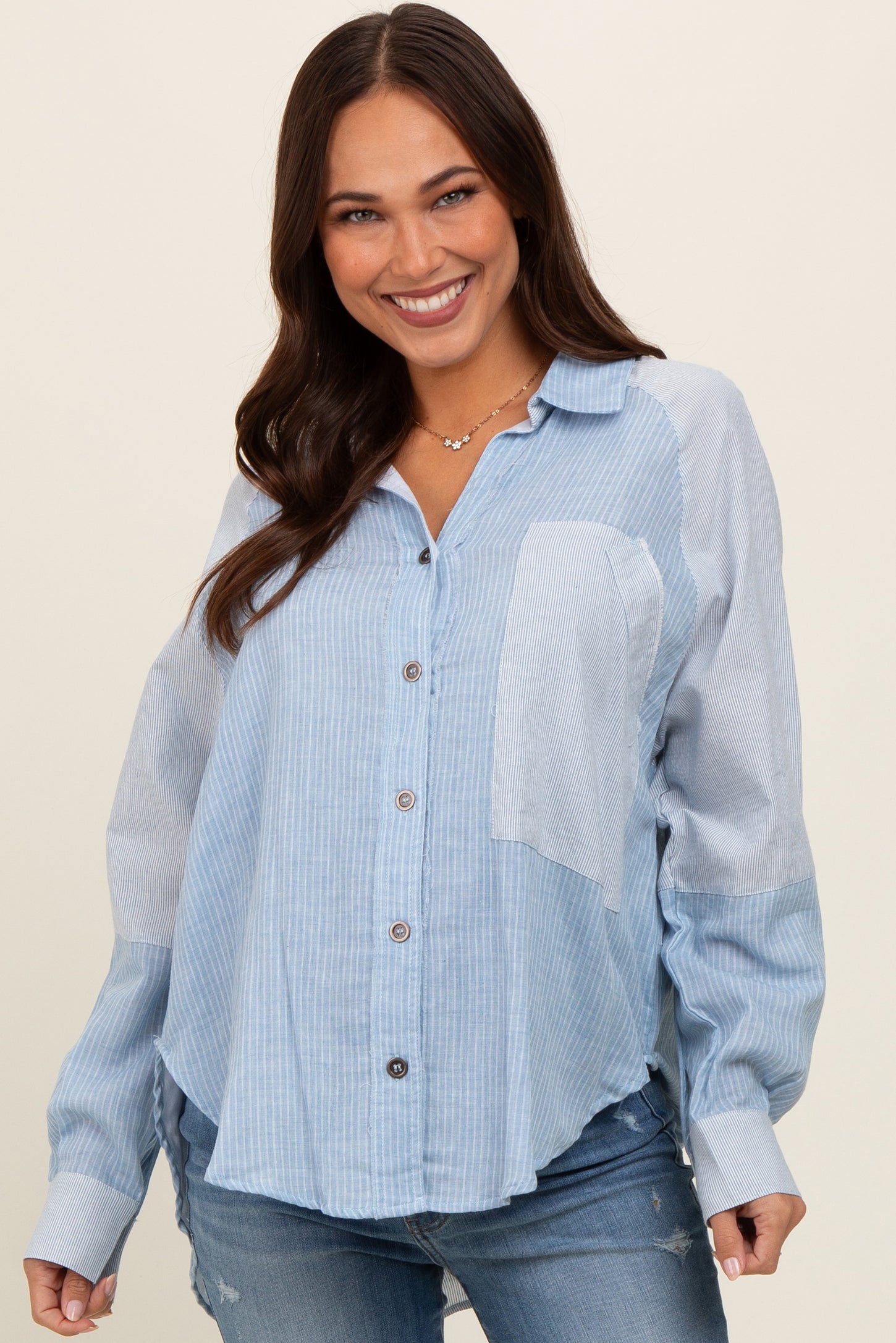 woman wearing a light blue button-up maternity shirt with striped pattern and long sleeves, smiling at the camera