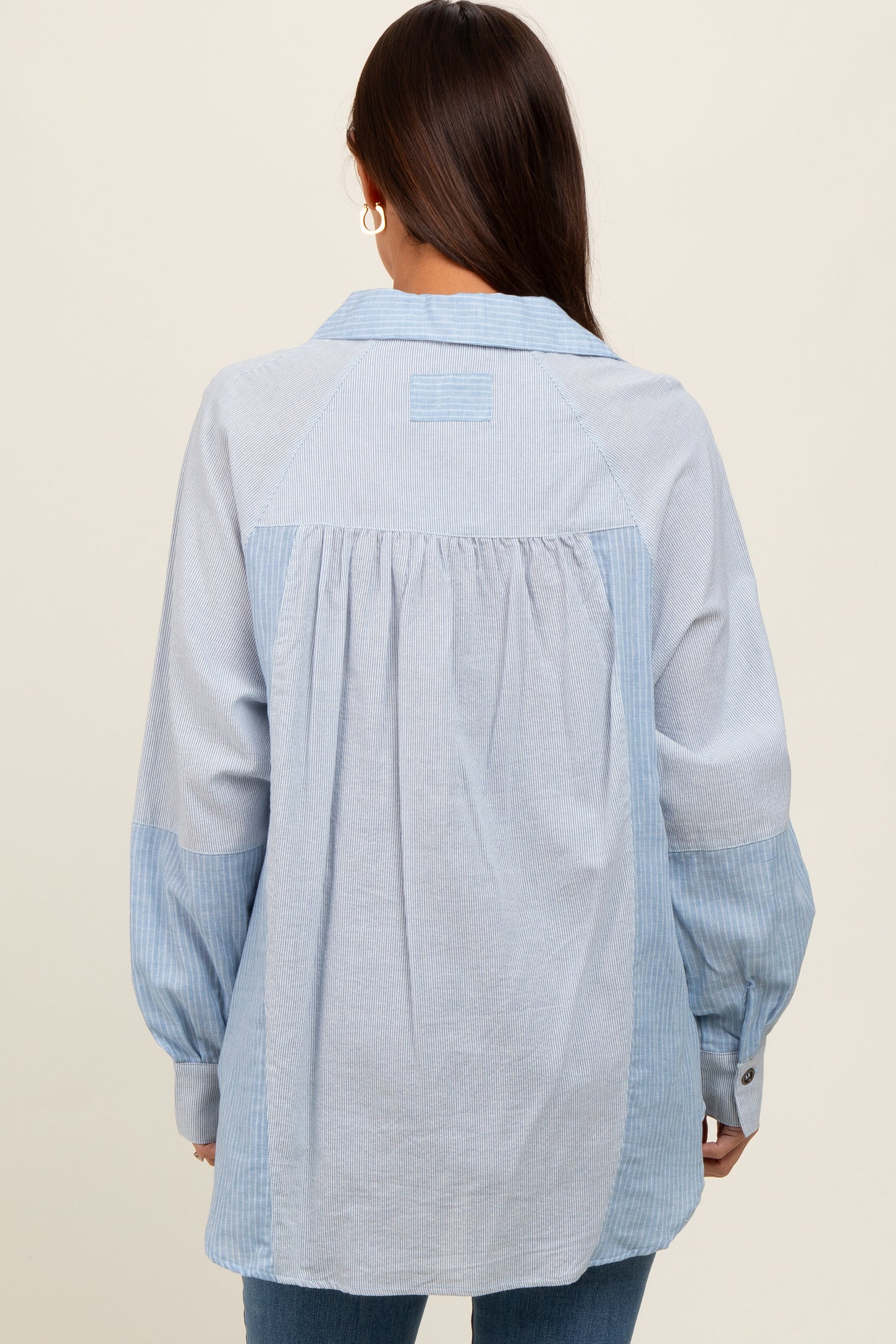 woman wearing a light blue striped maternity shirt with a relaxed fit and gathered back detail