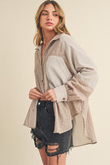 woman wearing a beige and gray striped button-up shirt with a relaxed fit and black distressed shorts