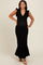woman wearing a black ribbed maternity dress with ruffled sleeves and a flared bottom, showing her baby bump
