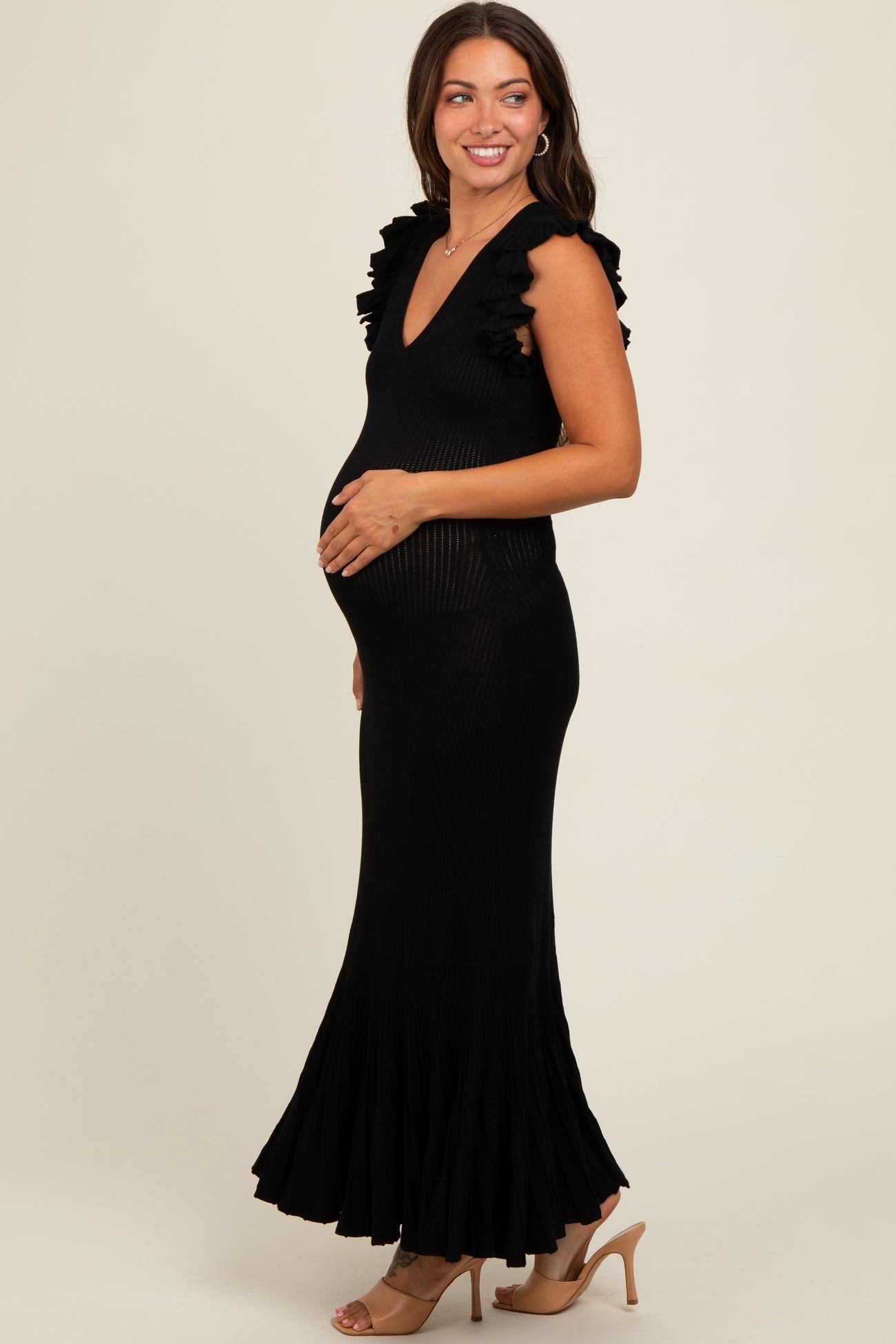 woman wearing a black sleeveless ribbed maternity dress with ruffle details and a visible baby bump