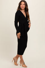 woman wearing a black ribbed maternity wrap dress with a tie waist and a visible baby bump