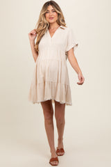 woman wearing a beige maternity dress with a tiered hem and short sleeves, showing her baby bump