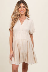 woman wearing a beige short sleeve maternity dress with a tiered hem and collar
