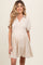 woman wearing a beige short sleeve maternity dress with a tiered hem and collar
