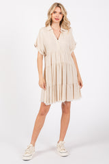 woman wearing a beige short sleeve tiered dress with a v-neckline and frayed hem, paired with white sneakers