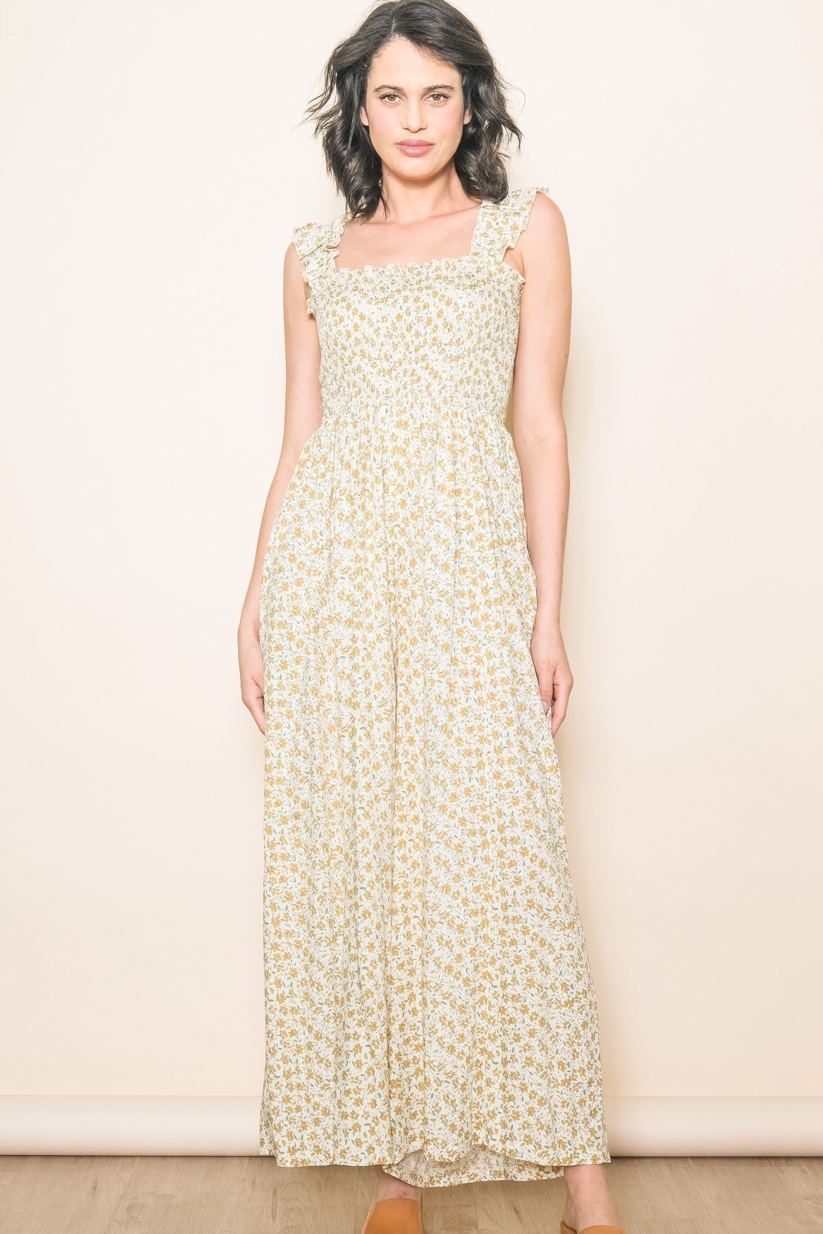 woman wearing a floral maxi dress with ruffled straps in cream and yellow