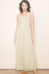 woman wearing a floral maxi dress with ruffled straps in cream and yellow