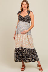 woman wearing a floral maternity maxi dress with tie straps and a baby bump, standing in a relaxed pose