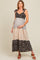 woman wearing a floral maternity maxi dress with tie straps and a baby bump, standing in a relaxed pose