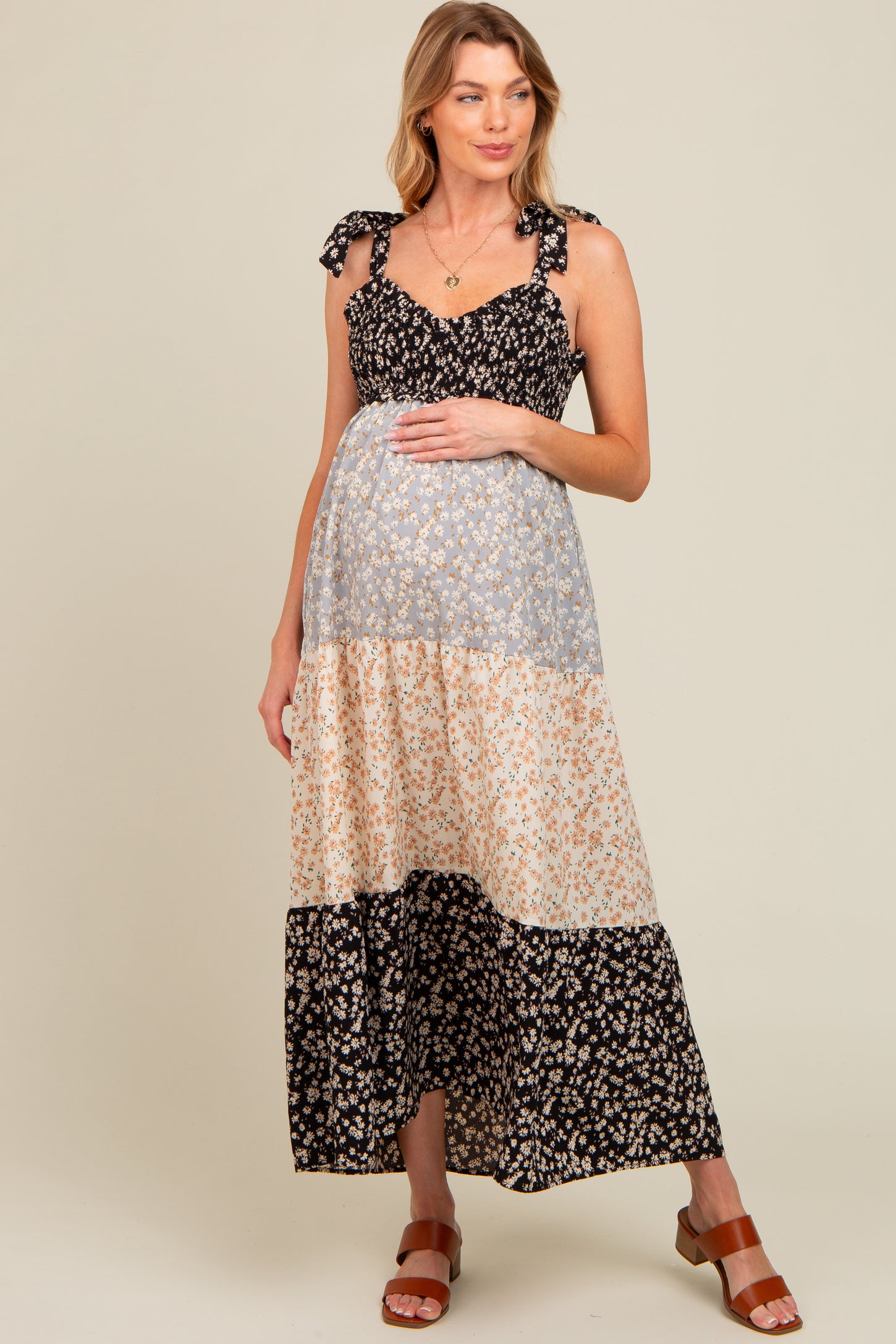 woman wearing a black and cream floral maternity maxi dress with tie straps and a visible baby bump