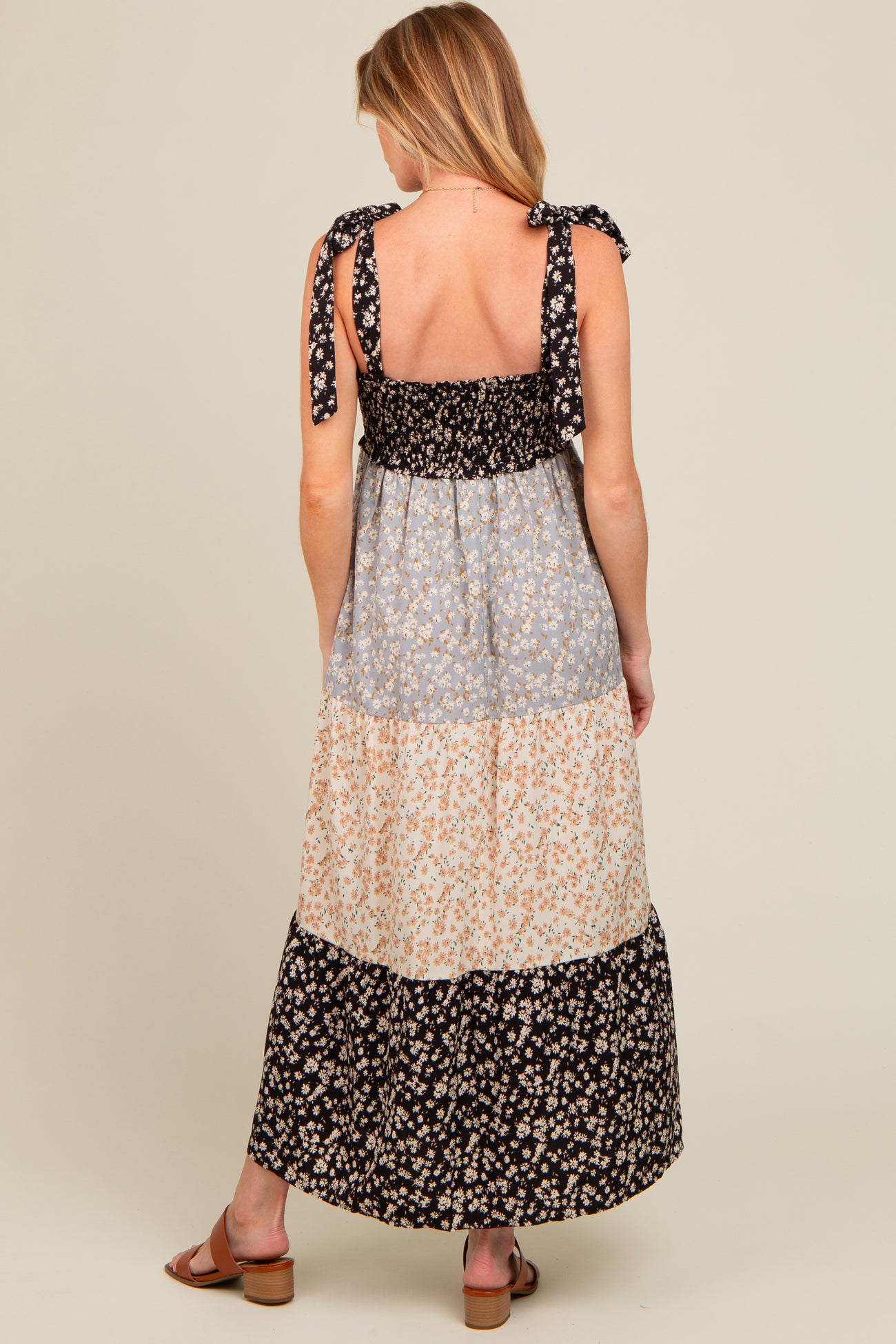 woman wearing a floral print maternity maxi dress with tie shoulder straps and a tiered design, back view