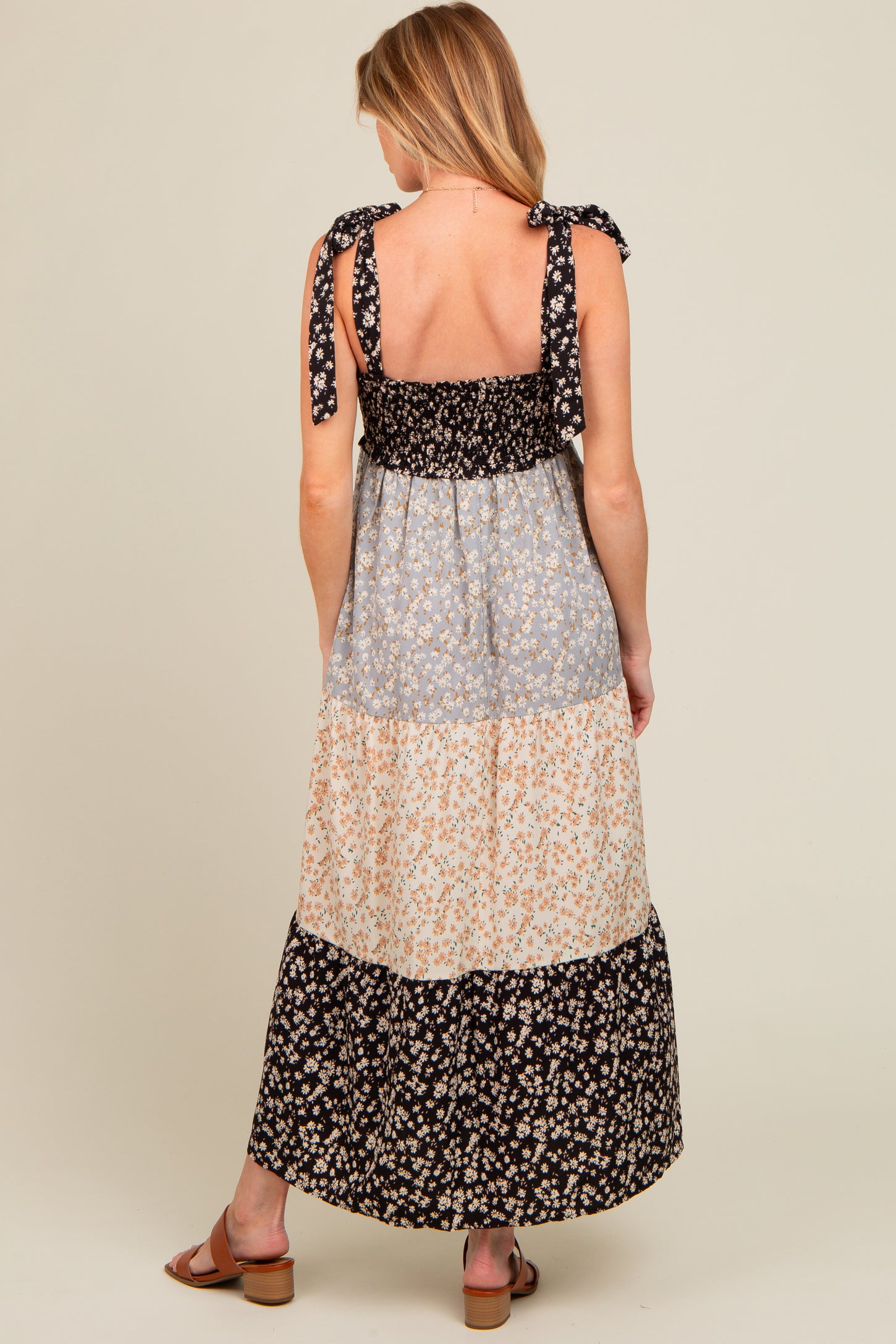 woman wearing a floral print maternity maxi dress with tie shoulder straps and a tiered design, back view