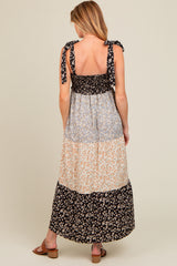 woman wearing a floral print maternity maxi dress with tie shoulder straps and a tiered design, back view