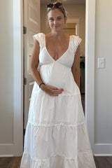 woman wearing a white maternity dress with a tiered skirt and puff sleeves, holding her baby bump