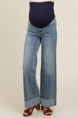 woman wearing blue maternity jeans with a wide leg and cuffed hem, showing her baby bump