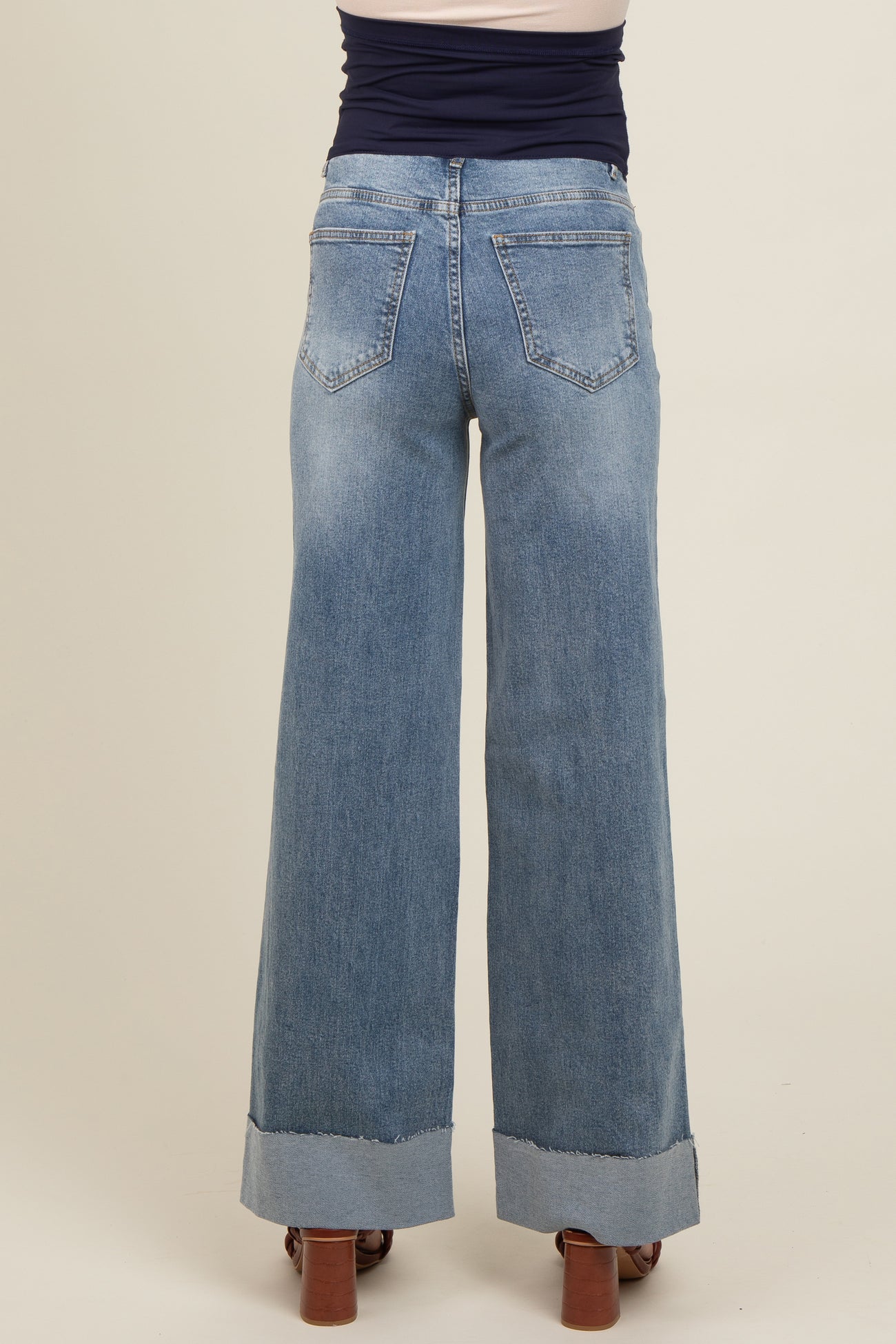 woman wearing light blue wide-leg maternity jeans with a frayed hem, viewed from the back