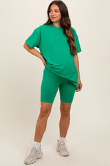 woman wearing a green oversized t-shirt and matching bike shorts, showcasing a baby bump in maternity wear