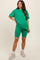 woman wearing a green oversized t-shirt and matching bike shorts, showcasing a baby bump in maternity wear