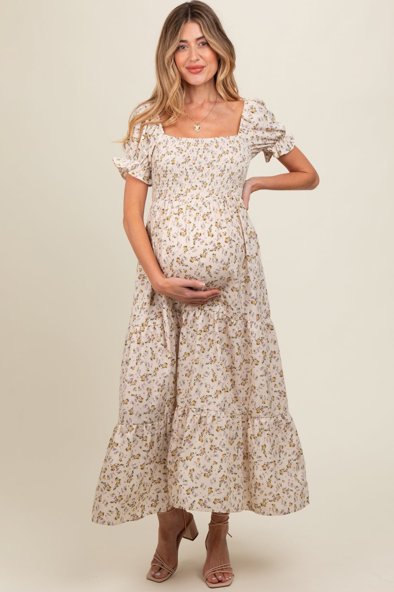 woman wearing a floral maternity dress with puff sleeves and tiered skirt, showing her baby bump