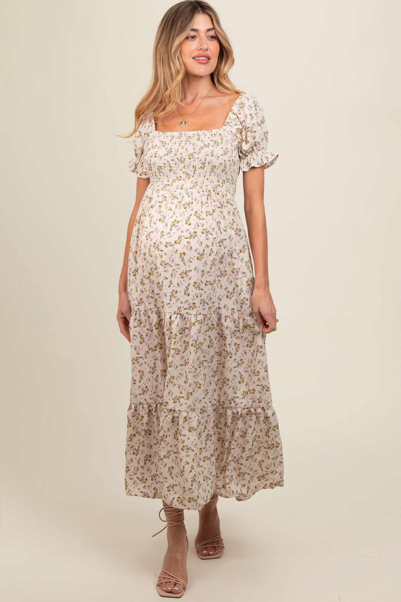 woman wearing a floral print maternity maxi dress with puff sleeves and a smocked bodice, showcasing her baby bump